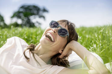 Portrait of laughing relaxed woman lying on a meadow - FMKF05769