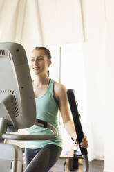 Young woman exercising on step machine in fitness gym - SEBF00131