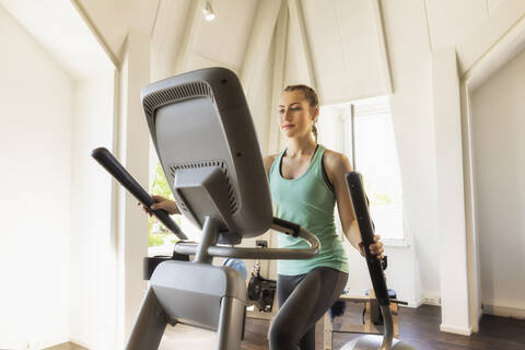 Junge Frau trainiert auf einem Stepper im Fitnessstudio, lizenzfreies Stockfoto