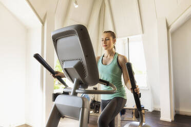 Junge Frau trainiert auf einem Stepper im Fitnessstudio - SEBF00135