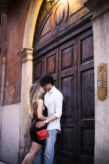 Verliebtes junges Paar an einer Holztür in der Stadt - GIOF07013