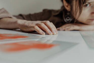 Female artist leaning on table with broken glass in her studio - OGF00107