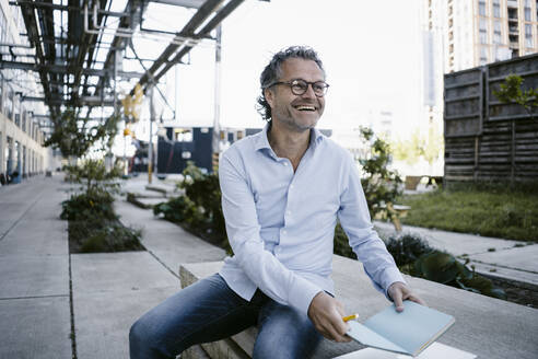 Portrait of smiling mature man with notebook - KNSF06122