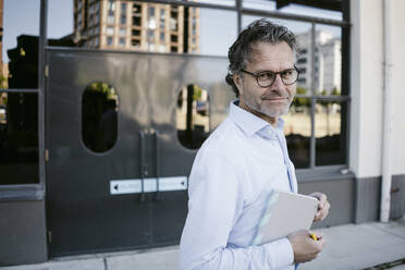 Portrait of smiling mature man with notebook - KNSF06126