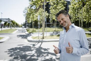 Portrait of smiling mature man with thumbs up - KNSF06137