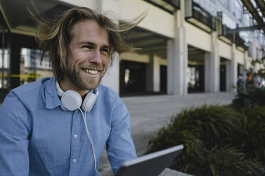 Happy young man with tablet outside - KNSF06169