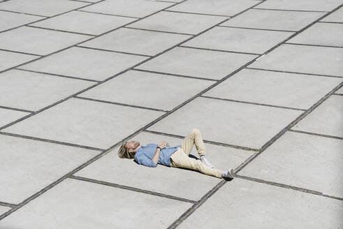 Junger Mann auf einem Platz liegend - KNSF06181