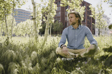 Young man sitting in urban park - KNSF06186