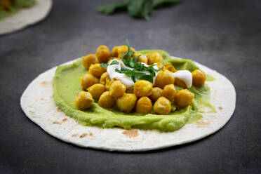 Nahaufnahme von Fladenbrot garniert mit Avocadocreme und Kurkuma-Kichererbsen auf dem Tisch - LVF08228