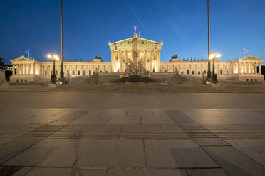 Außenansicht des beleuchteten österreichischen Parlamentsgebäudes in Wien gegen einen klaren blauen Himmel bei Nacht - TAMF02037