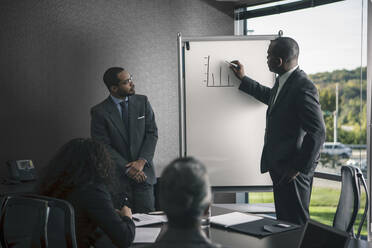 Businessman talking to colleagues in meeting - BLEF13515