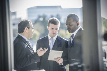 Businessmen using digital tablet outside office - BLEF13529