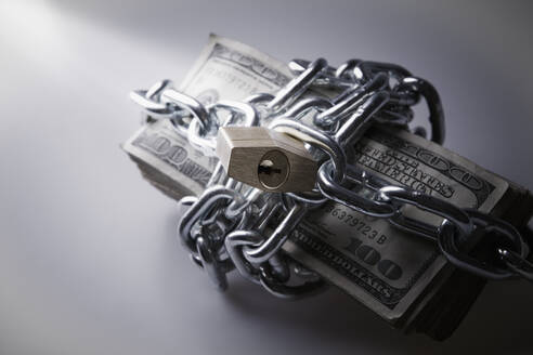 Chains and padlock around stack of dollar bills - BLEF13601