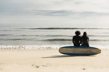 Surfer sitzen auf einem Brett am Strand - BLEF13619