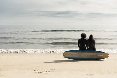 Surfers sitting on board on beach - BLEF13619