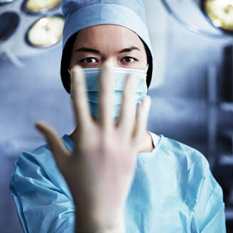 Kaukasischer Chirurg zieht Handschuh im Operationssaal an - BLEF13626