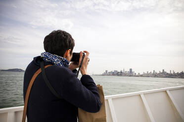 Woman taking picture of city skyline, San Francisco, California, United States - BLEF13646