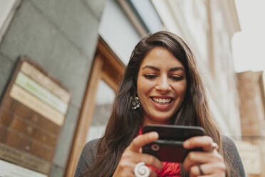 Mixed race woman using cell phone outdoors - BLEF13668