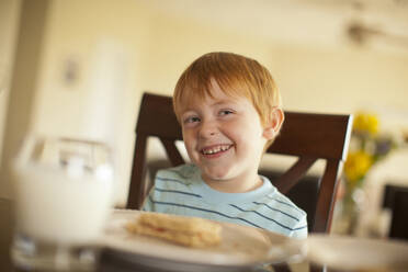 Caucasian boy giggling at dinner table - BLEF13671