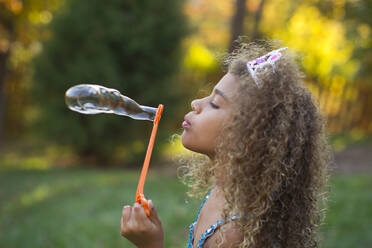 Mixed race girl blowing bubbles outdoors - BLEF13672
