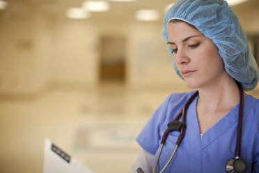 Kaukasische Krankenschwester liest Krankenblatt im Krankenhaus - BLEF13694