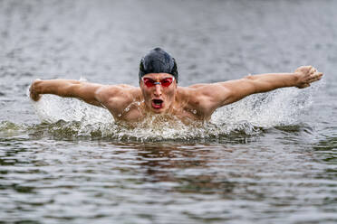 Junger Triathlet beim Schwimmen in einem See - STSF02168