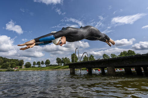 Junge Triathletin springt in einen See - STSF02170