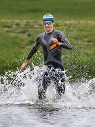 Junger Triathlet läuft in einen See - STSF02173