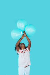 Little girl In front of a blue wall, holding balloons - JCMF00083