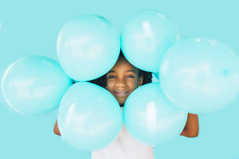 Kleines Mädchen vor einer blauen Wand, mit Luftballons, lizenzfreies Stockfoto