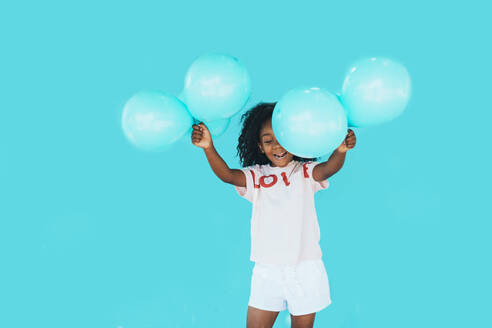 Little girl In front of a blue wall, holding balloons - JCMF00090