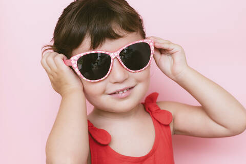Happy Little girl wearing sunglasses on pink background, lizenzfreies Stockfoto