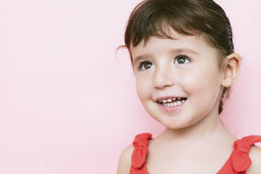 Portrait of smiling little girl in front of pink background looking up - GEMF03041