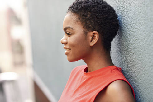 Profile of smiling young woman leaning against wall - JSMF01195