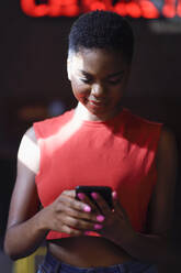 Portrait of smiling young woman looking at cell phone - JSMF01201