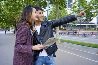 Touristenpaar, das die Stadt besichtigt und einen Stadtplan in der Hand hält, Barcelona, Spanien - GEMF03044