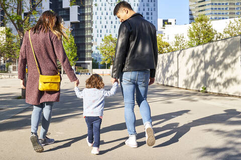 Eltern und kleines Mädchen halten sich an den Händen und gehen zusammen in Barcelona, Spanien, lizenzfreies Stockfoto