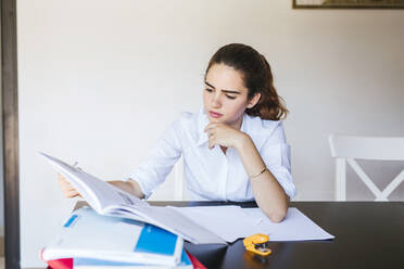 Focused female student learning at desk at home - LJF00584