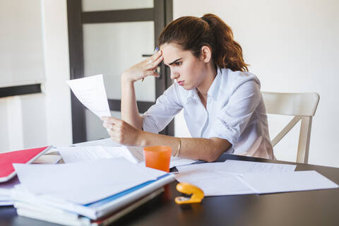 Female student with documents at desk at home stock photo
