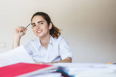 Lächelnde Studentin beim Lernen am Schreibtisch zu Hause - LJF00603