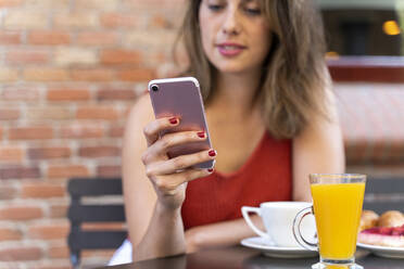 Die Hand einer jungen Frau in einem Straßencafé hält ein Smartphone, Nahaufnahme - AFVF03625