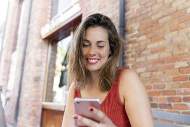 Portrait of smiling young woman looking at cell phone - AFVF03636