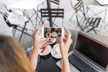 Junge Bloggerin sitzt in einem Straßencafé und fotografiert das Essen, Teilansicht - AFVF03640