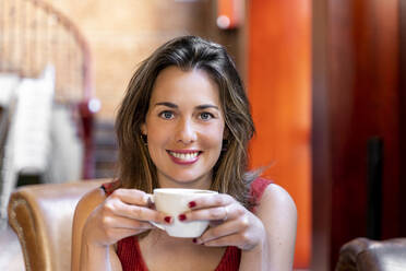 Porträt einer lächelnden jungen Frau mit einer Tasse Kaffee - AFVF03646