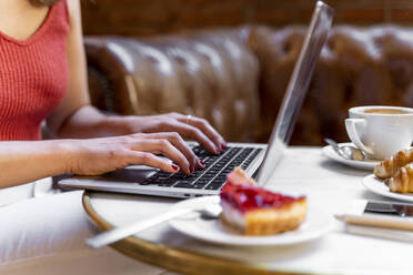 Junge Bloggerin arbeitet am Laptop in einem Café, Teilansicht - AFVF03647