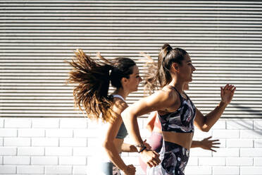 Three sporty young women running in the city - OCMF00542