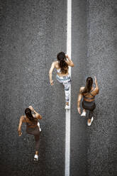 Top view of three sporty young women running on a street - OCMF00548