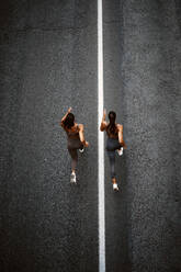 Top view of two sporty twin sisters running on a street - OCMF00550