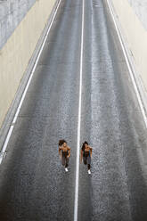 Top view of two sporty twin sisters running on a street - OCMF00551