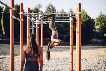 Two young women doing workout on calisthenics bars - OCMF00556